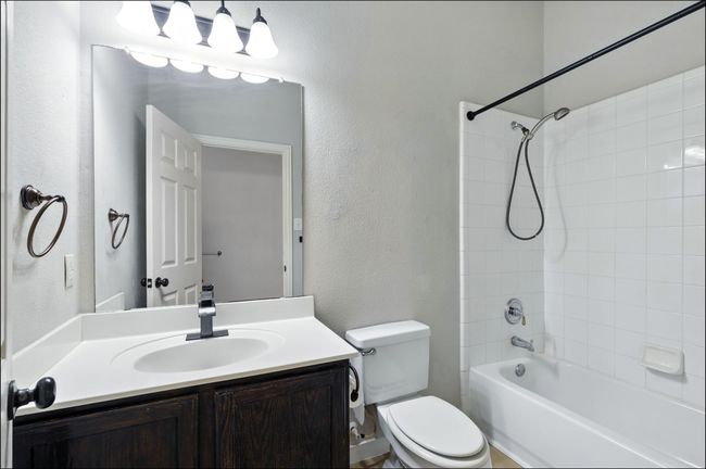 Full bathroom with vanity, tub / shower combination, and a textured wall | Image 8
