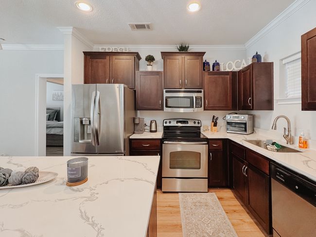 Kitchen featuring visible vents, light wood-style flooring, stainless steel appliances, crown molding, and a sink | Image 6