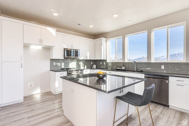 Kitchen with appliances with stainless steel finishes, dark stone countertops, light wood-style floors, white cabinets, and recessed lighting | Image 8
