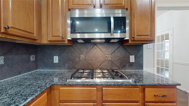 Elegant kitchen featuring a gas cooktop and sleek stainless-steel microwave. | Image 15