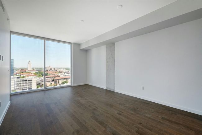 Living area with a view of city, wood-style flooring, baseboards, and a wall of windows | Image 6