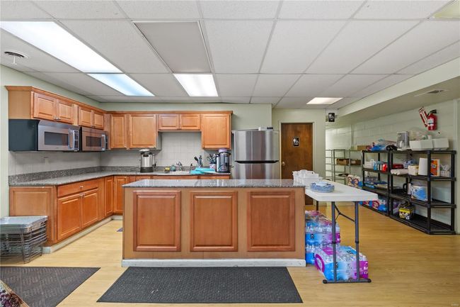 Kitchen with visible vents, a center island, light wood-type flooring, appliances with stainless steel finishes, and a sink | Image 19
