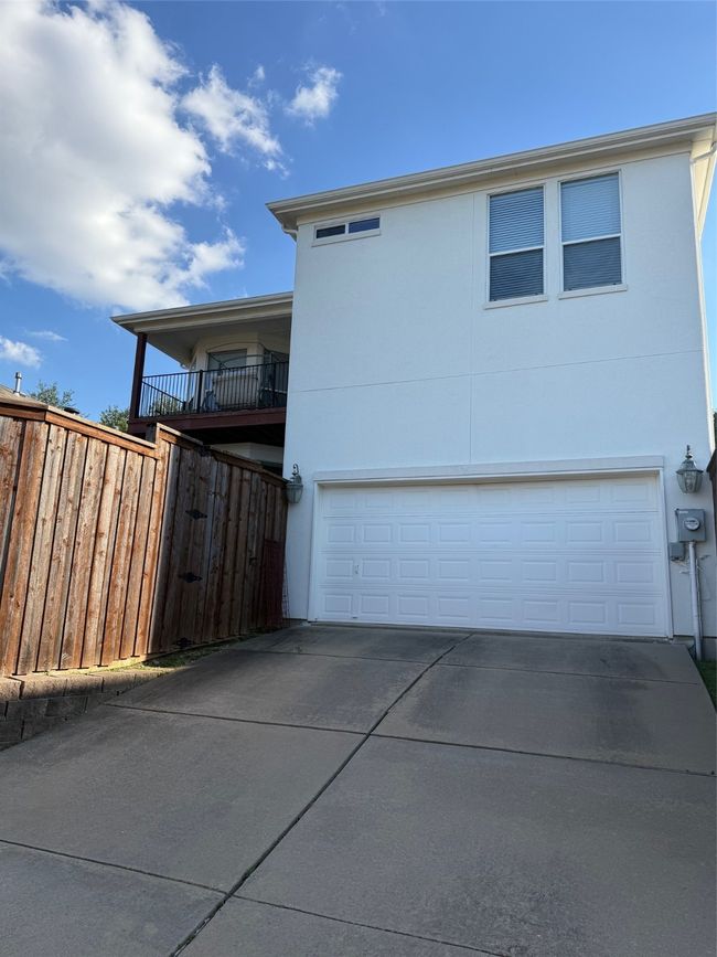 View of side of home with an attached garage, driveway, fence, and stucco siding | Image 4