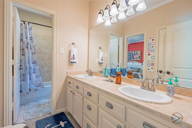 Bathroom featuring double sink, shower / tub combo with curtain, and large vanity | Image 16