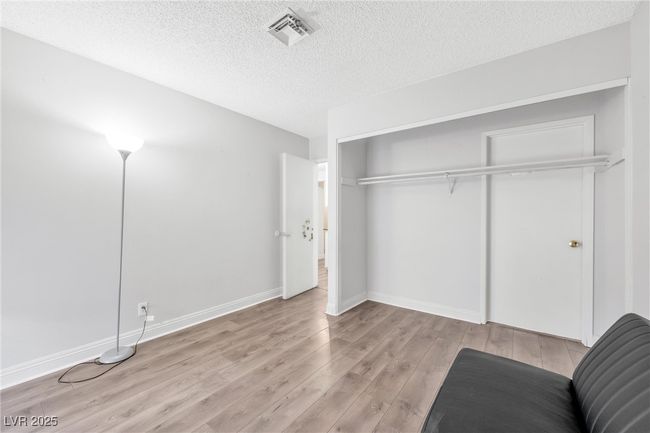 Bedroom with a textured ceiling, visible vents, a closet, baseboards, and wood finished floors | Image 13