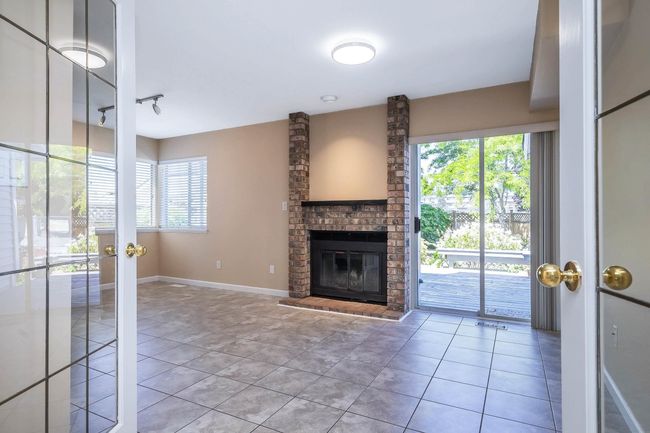 Unfurnished living room with a wealth of natural light, a fireplace, and tile patterned flooring | Image 10