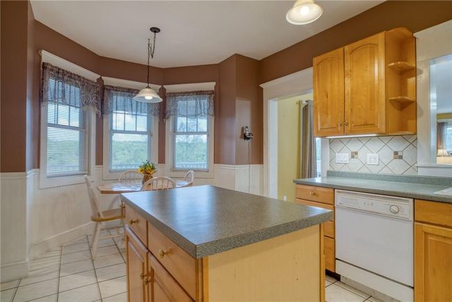 Kitchen with a center island, white dishwasher, tasteful backsplash, and light tile patterned floors | Image 9