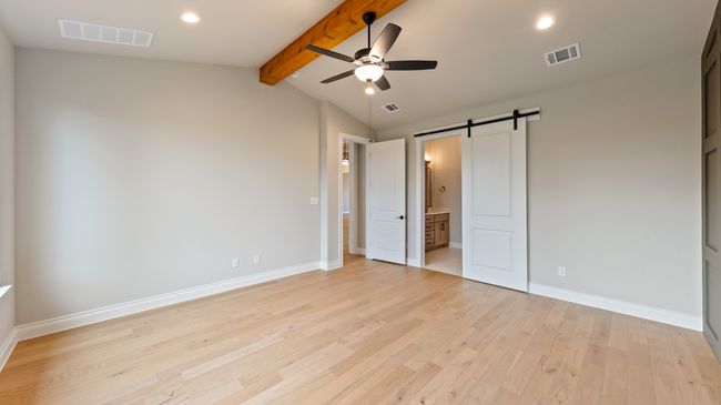 Unfurnished bedroom featuring a barn door, light wood-style floors, recessed lighting, connected bathroom, and ceiling fan | Image 24