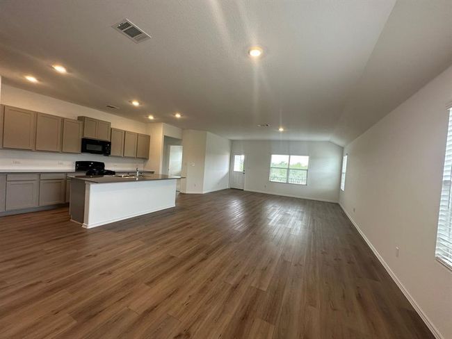 Kitchen featuring gray cabinets, black microwave, open floor plan, a sink, and dark wood-style floors | Image 17
