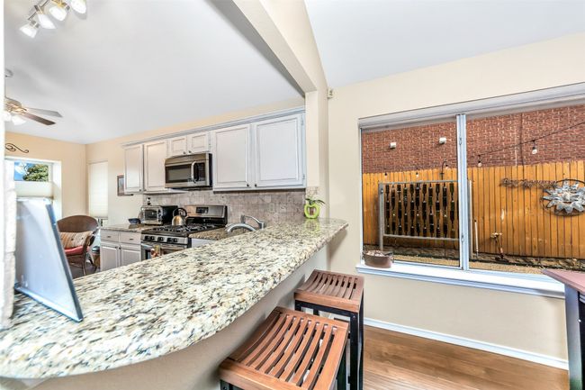 Kitchen featuring stainless steel appliances, backsplash, wood finished floors, baseboards, and ceiling fan | Image 8
