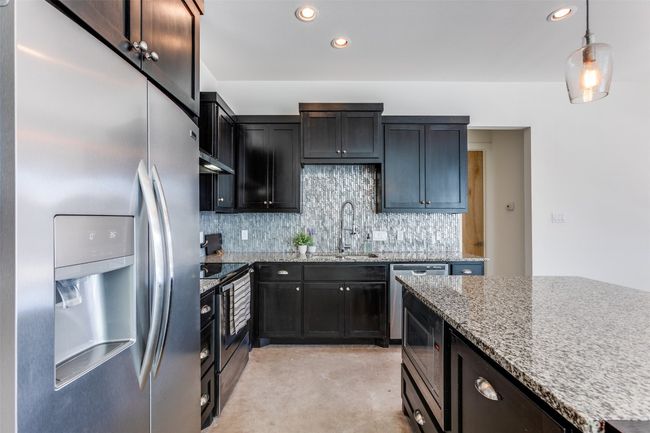 Kitchen featuring decorative backsplash, appliances with stainless steel finishes, decorative light fixtures, light stone countertops, and recessed lighting | Image 10