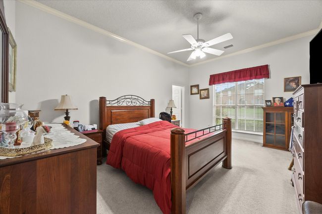 Bedroom featuring ornamental molding, light carpet, a ceiling fan, and a textured ceiling | Image 10