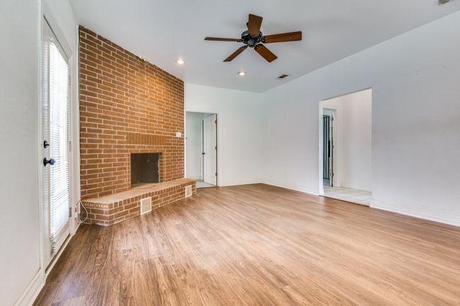 Unfurnished living room with wood finished floors, a fireplace, a ceiling fan, and recessed lighting | Image 5