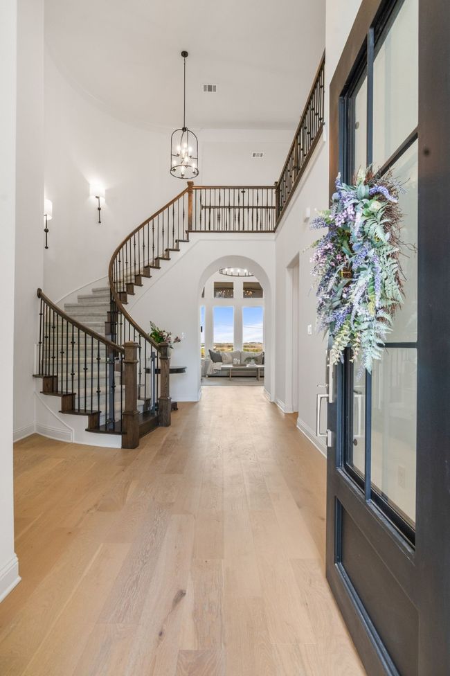 Entrance foyer with stairway, light wood-style floors, a towering ceiling, a chandelier, and arched walkways | Image 4