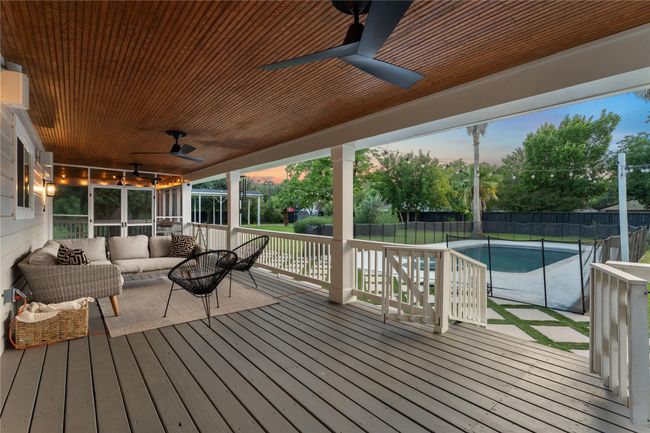 Step into a large second porch with 4 patio fans, outdoor speakers, and stained beadboard ceiling | Image 25