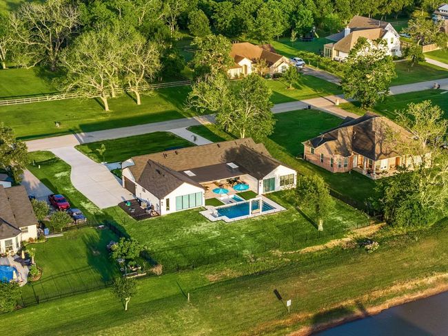 Set on a spacious waterfront lot, this stunning property offers the ultimate in outdoor living with a beautifully designed pool, expansive patio, and private yard. Located in a peaceful neighborhood with mature trees and wide open green spaces, it’s the perfect blend of luxury and tranquility. | Image 42
