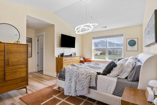 Bedroom with a notable chandelier, baseboards, light wood-style flooring, visible vents, and lofted ceiling | Image 16