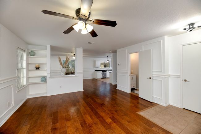 Unfurnished living room with built in shelves, dark engineered wood floors, visible vents, and ceiling fan | Image 5