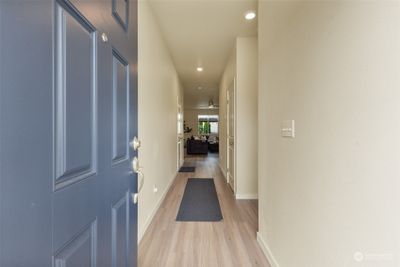 Welcome home! As you step through the front door, you're greeted by a bright and inviting hallway that leads you into the heart of the home. The modern, neutral-toned walls and sleek laminate flooring create a clean and contemporary feel, offering a warm welcome to all who enter. The long entryway provides a seamless flow from the front door to the open living space, giving the home an airy and connected atmosphere. | Image 3