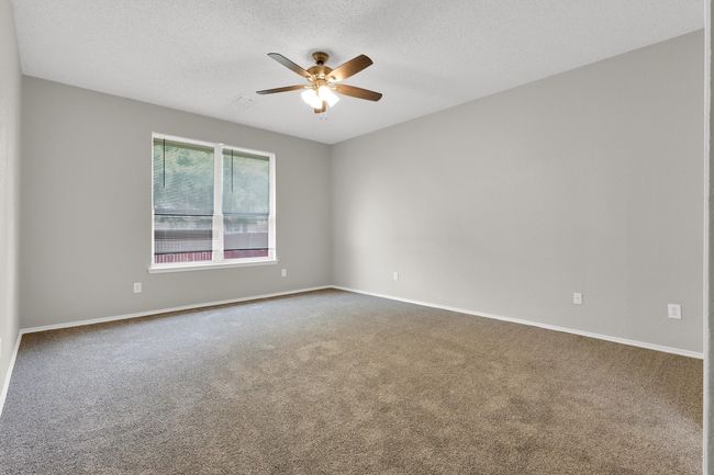 Carpeted empty room with a ceiling fan, a textured ceiling, and baseboards | Image 18