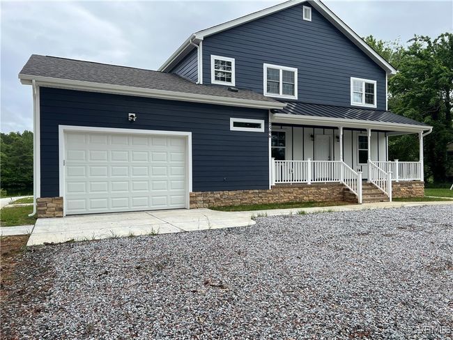 View of front of house with covered porch, board and batten siding, a garage, and gravel driveway | Image 33