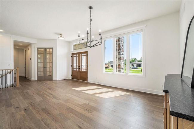 Unfurnished dining area with french doors, wood finished floors, a chandelier, plenty of natural light, and recessed lighting | Image 12