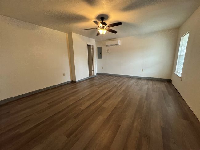 Spare room with a wall unit AC, electric panel, ceiling fan, dark wood-type flooring, and a textured ceiling | Image 22