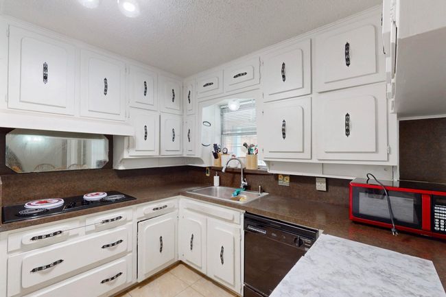 Kitchen with white cabinets, a sink, black appliances, and a textured ceiling | Image 14