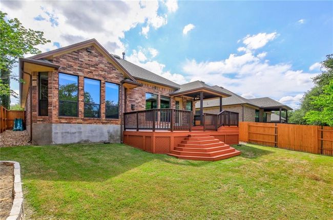 Rear view of property with a fenced backyard, brick siding, a deck, and stairs | Image 34