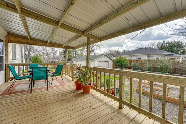 Wooden terrace featuring fence, an outdoor structure, outdoor dining area, and a detached garage | Image 22