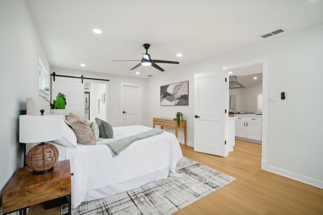 Bedroom featuring visible vents, light wood-style flooring, recessed lighting, a barn door, and baseboards | Image 13
