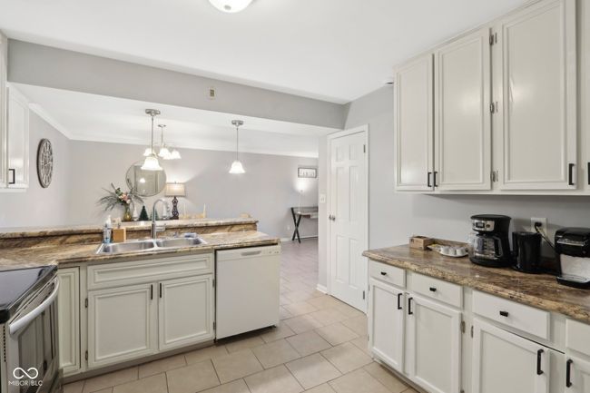 kitchen featuring dishwasher, electric stove, light tile patterned floors, a sink, and hanging light fixtures | Image 12