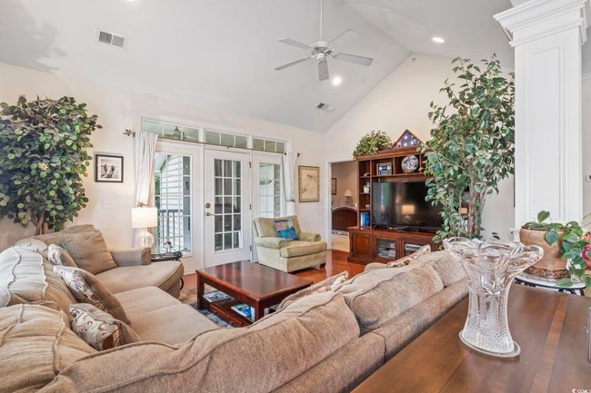 Living room with a ceiling fan, french doors, high vaulted ceiling, wood finished floors, and decorative columns | Image 24