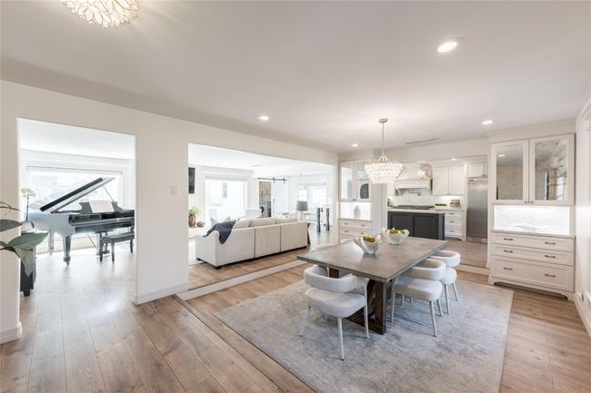 This large and bright, open-concept home features a modern kitchen with sleek cabinetry, a cozy living area, a spacious dining area that is perfect for entertaining and family living. | Image 6