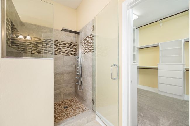The primary bath offers a luxurious, spa-like experience with dual sinks, a jetted soaking tub, and a seamless glass shower. Designed for both comfort and functionality, it features ample counter space and storage, creating a clean and elegant atmosphere. | Image 17