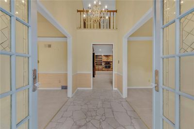 Foyer featuring carpet flooring, a high ceiling, and a chandelier | Image 3