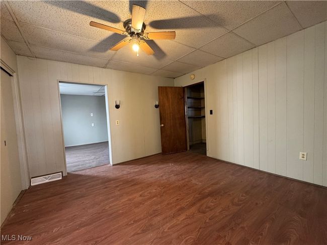Spare room with ceiling fan, a paneled ceiling, wood finished floors, and visible vents | Image 6