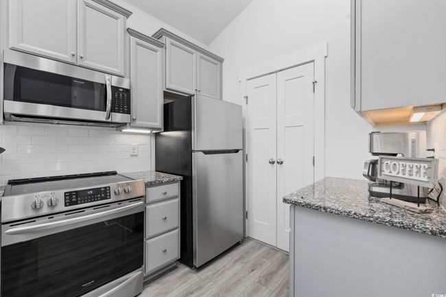 Kitchen with backsplash, gray cabinetry, light wood-style floors, and appliances with stainless steel finishes | Image 10