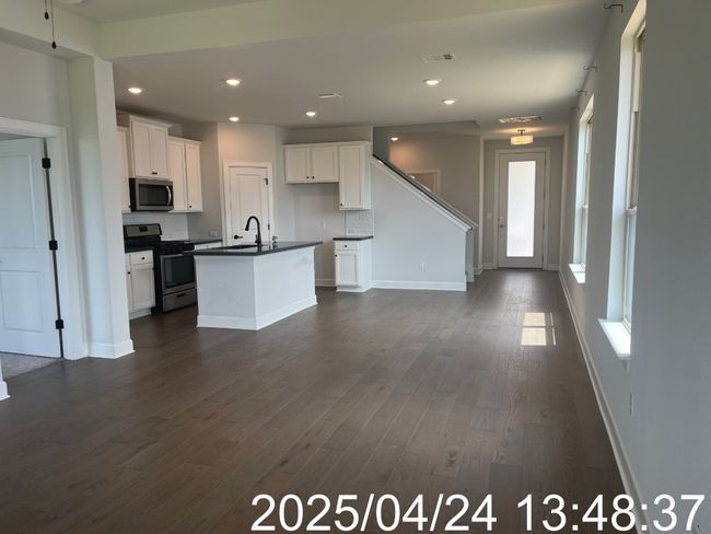Kitchen with white cabinets, dark countertops, appliances with stainless steel finishes, a sink, and dark wood-type flooring | Image 34