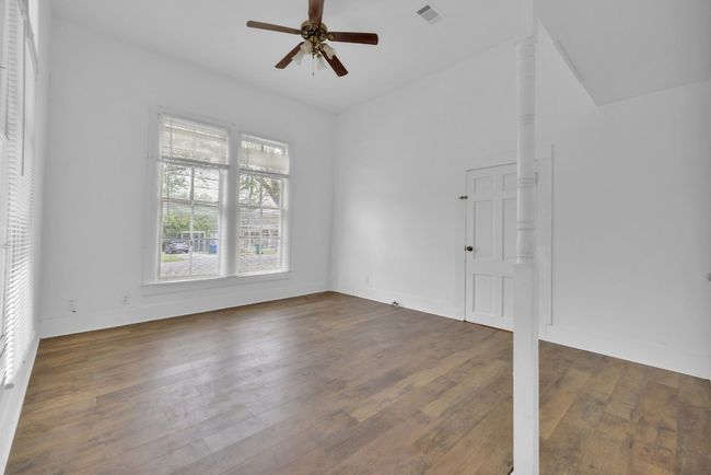 Empty room with hardwood / wood-style flooring, ceiling fan, baseboards, lofted ceiling, and visible vents | Image 17