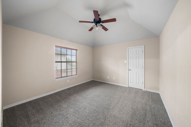 Carpeted empty room featuring baseboards, lofted ceiling, and ceiling fan | Image 33