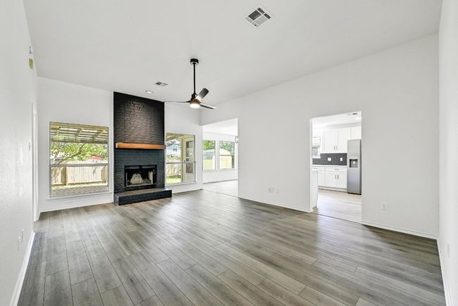 Unfurnished living room with ceiling fan, a fireplace, and wood finished floors | Image 4