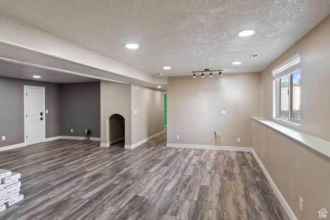 Basement with a textured ceiling, visible vents, wood finished floors, and baseboards | Image 29