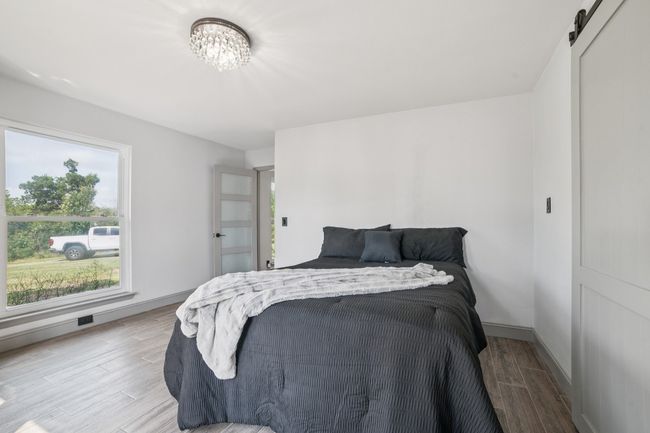 Private primary bedroom featuring a barn door, access to exterior, french doors, and tile flooring | Image 16