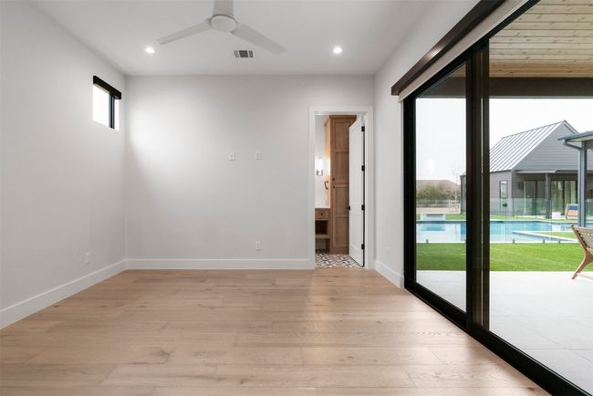 This main-floor guest bedroom feels like a private getaway, featuring its own ensuite bath and seamless access to the backyard, where guests can step outside and enjoy the peaceful surroundings | Image 21