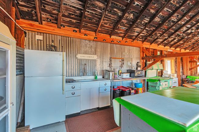Kitchen with wood walls, sink, lofted ceiling, and white fridge | Image 16