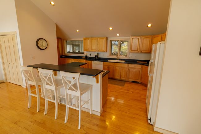 Kitchen with light hardwood / wood-style floors, white appliances, a kitchen island, a breakfast bar, and sink | Image 21