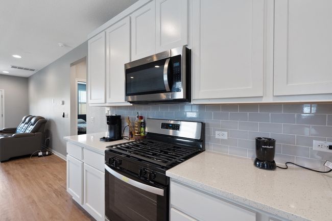 Kitchen featuring appliances with stainless steel finishes, white cabinets, tasteful backsplash, light wood-style flooring, and recessed lighting | Image 6