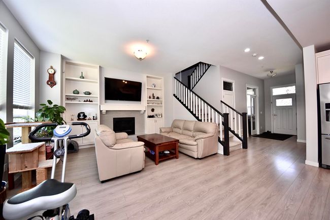 Living room with healthy amount of natural light, stairs, light wood-style floors, a fireplace, and recessed lighting | Image 8