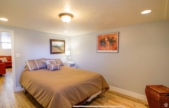 Bedroom with light wood-style flooring, a textured ceiling, baseboards, and recessed lighting | Image 14